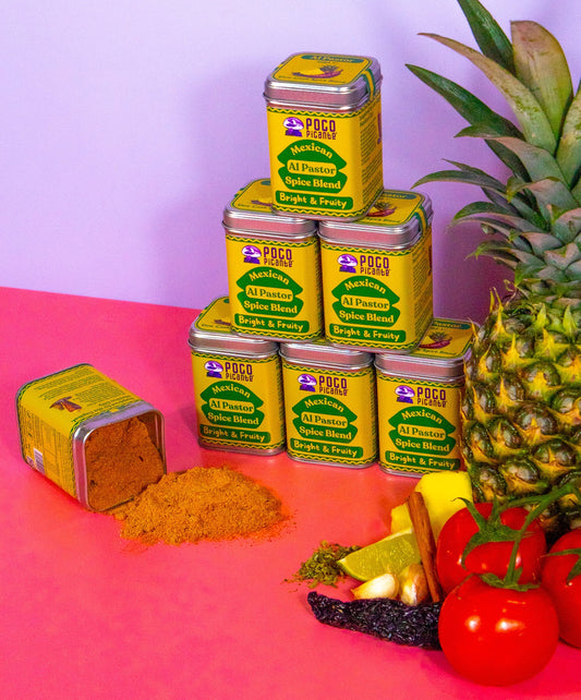 Packs of poco picante al pastor seasoning with a pineapple, tomatoes, and other ingredients on a pink and purple gradient background.